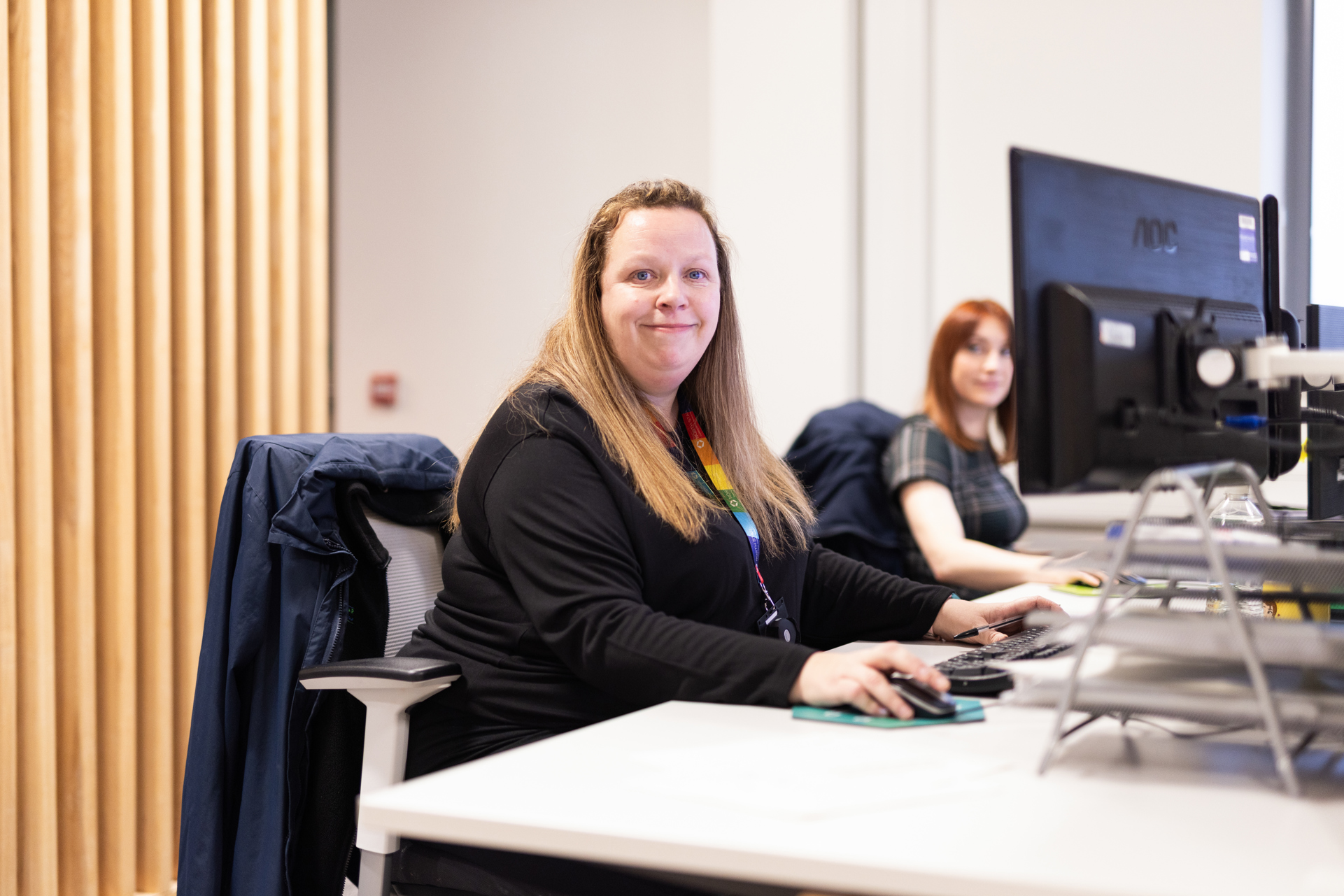 A person sat at a desk smiling towards the camera