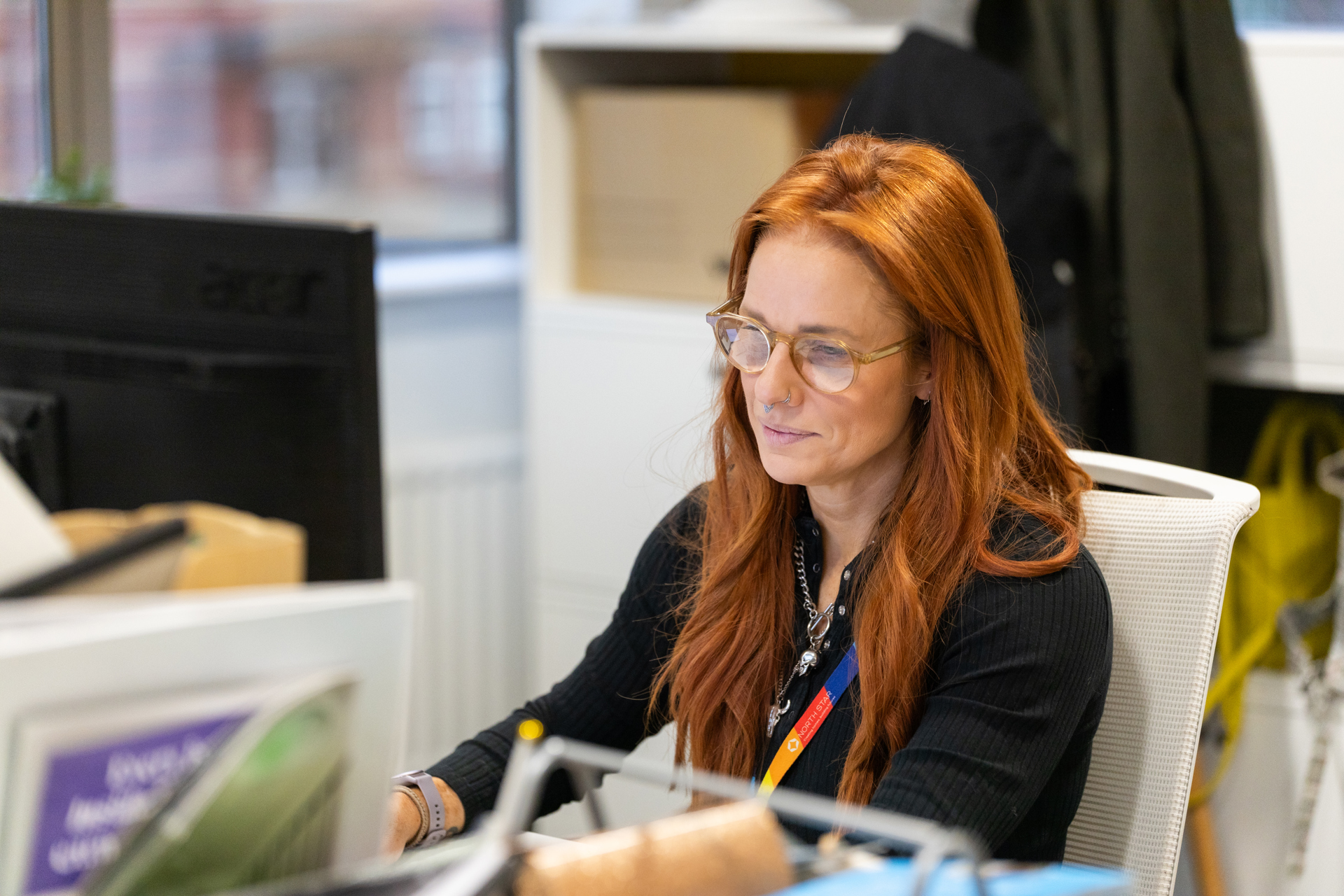 A person with glasses looks at a computer screen in an office